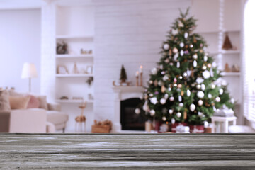 Empty wooden table in festively decorated room with Christmas tree near fireplace. Space for design
