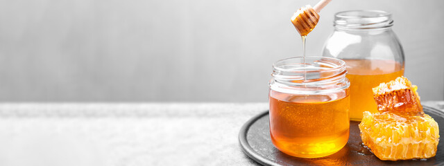 Tasty fresh aromatic honey on grey table, space for text. Banner design