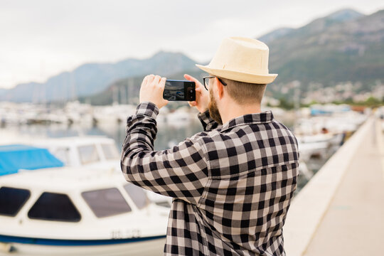 Traveller man taking pictures of luxury yachts marine during sunny day - travel and summer concept