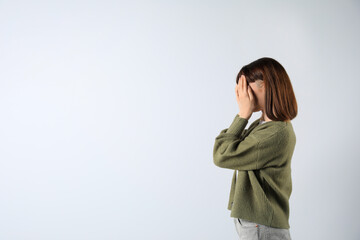 Young girl hiding face in hands on white background. Space for text