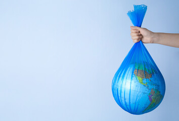 Woman holding plastic bag with globe and space for text on light background, closeup. Environmental...