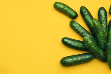 Fresh ripe cucumbers on yellow background, flat lay. Space for text