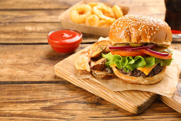 Tasty burger with potato wedges served on wooden table, space for text. Fast food