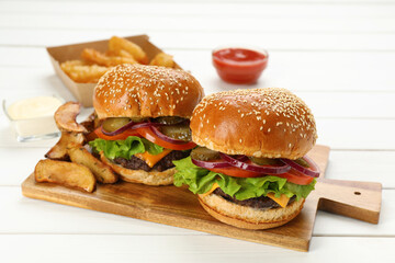 Tasty burgers served on white wooden table, closeup. Fast food