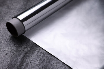 Roll of aluminum foil on grey table, closeup