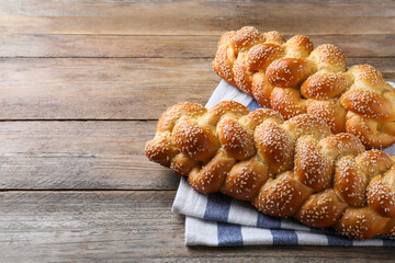 Homemade braided breads with sesame seeds on wooden table, space for text. Traditional Shabbat...