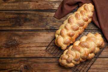 Homemade braided breads and cooling rack on wooden table, top view with space for text. Traditional...