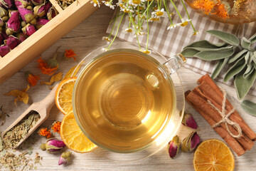 Freshly brewed tea and dried herbs on white wooden table, flat lay