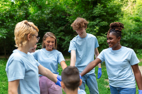 Group of multiracial volontaire young people building team outdoor in park, join hands together.