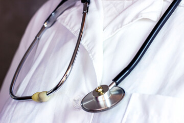 Black metal medical stethoscope on white doctor uniform in the hospital.