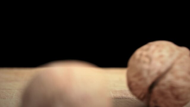 Walnut falls on a wooden surface in slow mo on a black background. Toughie. Nuts are good for the brain. Heap of walnuts close-up.