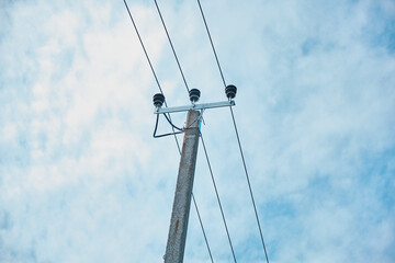 High voltage electric pylon and electrical wire at green rice field and tree forest with overcast...