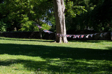 BEAUTIFUL OLD TREE IN SUNLIGHT WITH LINE OF BRITISH FLAGS  FLOATING IN THE BREEZE 