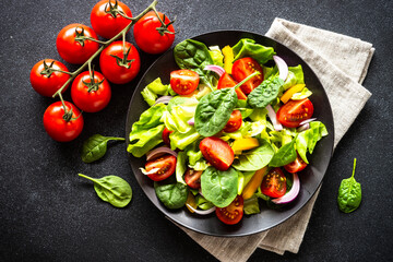 Fresh salad in black craft plate. Vegan meal. Top view with copy space.