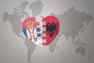 puzzle heart with the national flag of albania and serbia on a world map background.Concept.