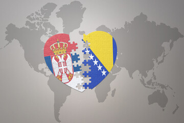 puzzle heart with the national flag of bosnia and herzegovina and serbia on a world map background.Concept.