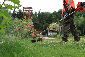 A gardener mows the grass in the garden with a brushcutter.
Ogrodnik kosi trawę w ogrodzie za pomocą wykaszarki. - obrazy, fototapety, plakaty