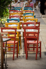Fototapeta na wymiar Clolored Wooden Chairs on Sidewalk in the City of Cagliari, in the Region of Sardinia, Italy, in Summer