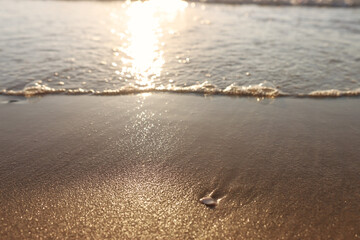Sea waves and warm sunset light, calm and relaxing sandy beach