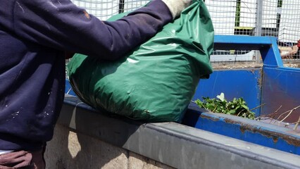 Man emptying garbage waste into landfill crate
