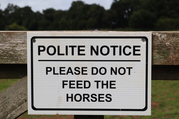 Sign on a farm gate saying Polite notice please do not feed the horses