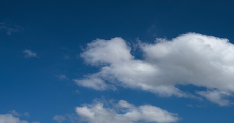 Sky overlay for digital art. Scenic white fluffy clouds moving softly across a clear blue sky