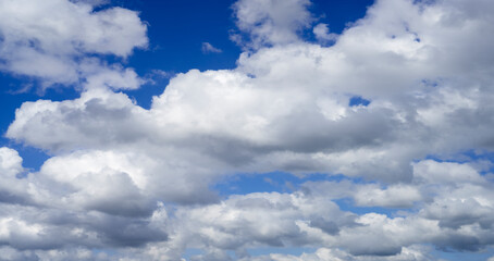 Sky overlay for digital art. Scenic white fluffy clouds moving softly across a clear blue sky