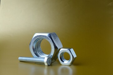 composition of new nuts and bolts of different sizes on a yellow background