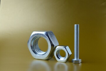 composition of new nuts and bolts of different sizes on a yellow background