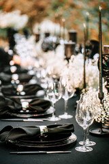 Serving and decorating a banquet table in black with white flowers and black candles at an outdoor party.