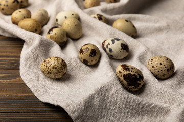 Quail eggs on a texture fabric on a brown wood background. Natural products. Place for text. Fresh quail eggs.