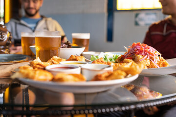 Table full of peruvian food and beer in a restaurant - obrazy, fototapety, plakaty