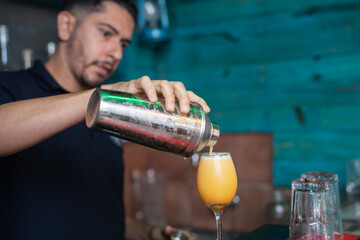 Man serving a cocktail in a crystal glass on a bar counter