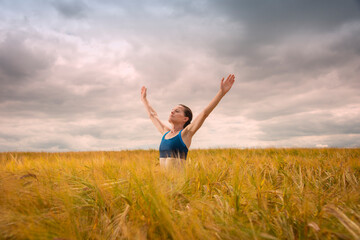 Woman with her arms raised in the middle of a field enjoying the summer and nature