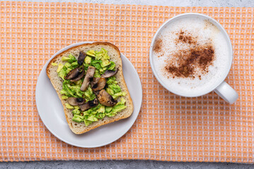 Avocado toast with mushrooms and cinnamon spiced coffee, top view