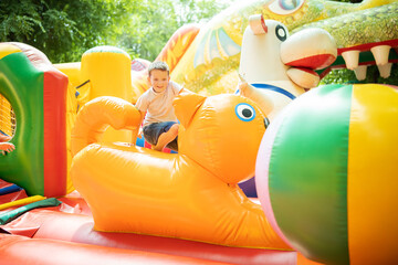 Happy boy having a lots of fun on a colorful inflate castle. Colorful playground. Activity and play...