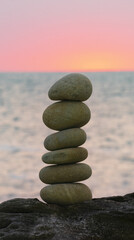 Stacked stone tower on the beach by the sea with the sunset out of focus.