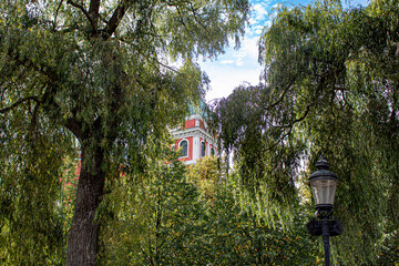 Peek-a-book View of St. Jacob’s Church through the Weeping Willow Trees in Kungsträdgården Park in Stockholm, Sweden
