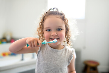 Little girl brushes her teeth with an toothbrush in the morning in the bathroom.