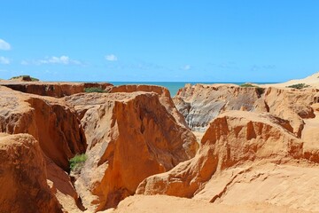 Fototapeta na wymiar Red cliffs and canyons in Morro Branco in Ceará., Brazil. Beauty constructed by the rain and wind erosion, near to the seashore
