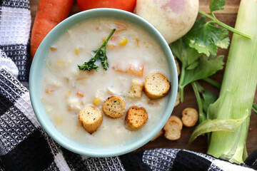 Chicken soup with croutons, carrots and corn. Winter comfort food with carrots, celery, leeks, turnip and tomato in the background 