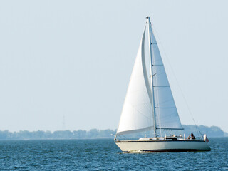 Obraz premium A white sailboat on blue water. 