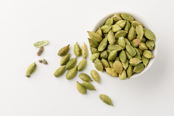Top view of aromatic condiment cardamom pods with seeds in a small white ceramic bowl