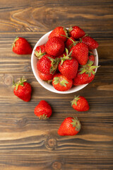 Fresh ripe strawberries in a bowl on a brown texture background.Vegetarian organic berry.Healthy food.Copy space.Place for text