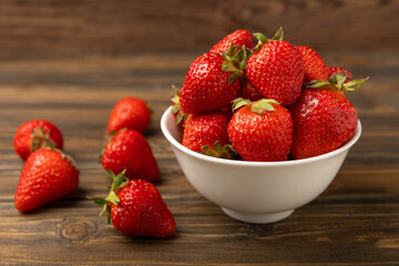 Fresh ripe strawberries in a bowl on a brown texture background.Vegetarian organic berry.Healthy food.Copy space.Place for text
