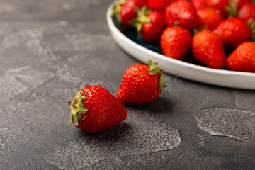 Fresh ripe strawberries in a plate on a black texture background.Vegetarian organic berry.Healthy food.Vitamins.Copy space.Place for text