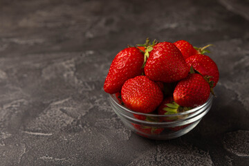 Fresh ripe strawberries in a plate on a black texture background.Vegetarian organic berry.Healthy food.Vitamins.Copy space.Place for text
