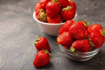 Fresh ripe strawberries in a plate on a black texture background.Vegetarian organic berry.Healthy food.Vitamins.Copy space.Place for text
