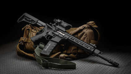 A modern automatic carbine with a collimator sight. The weapon lies on a military backpack. Rifle for the police, special forces or the army. Dark back. - obrazy, fototapety, plakaty