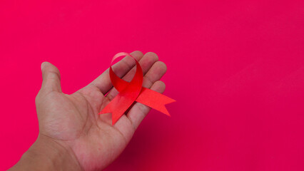 Hand holding a Red AIDS Ribbon with copy space for text isolated on red background